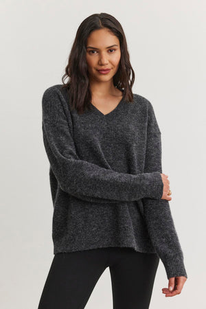 A person wearing the KELSA ALPACA SWEATER by Velvet by Graham & Spencer, paired with black pants, against a plain white background.