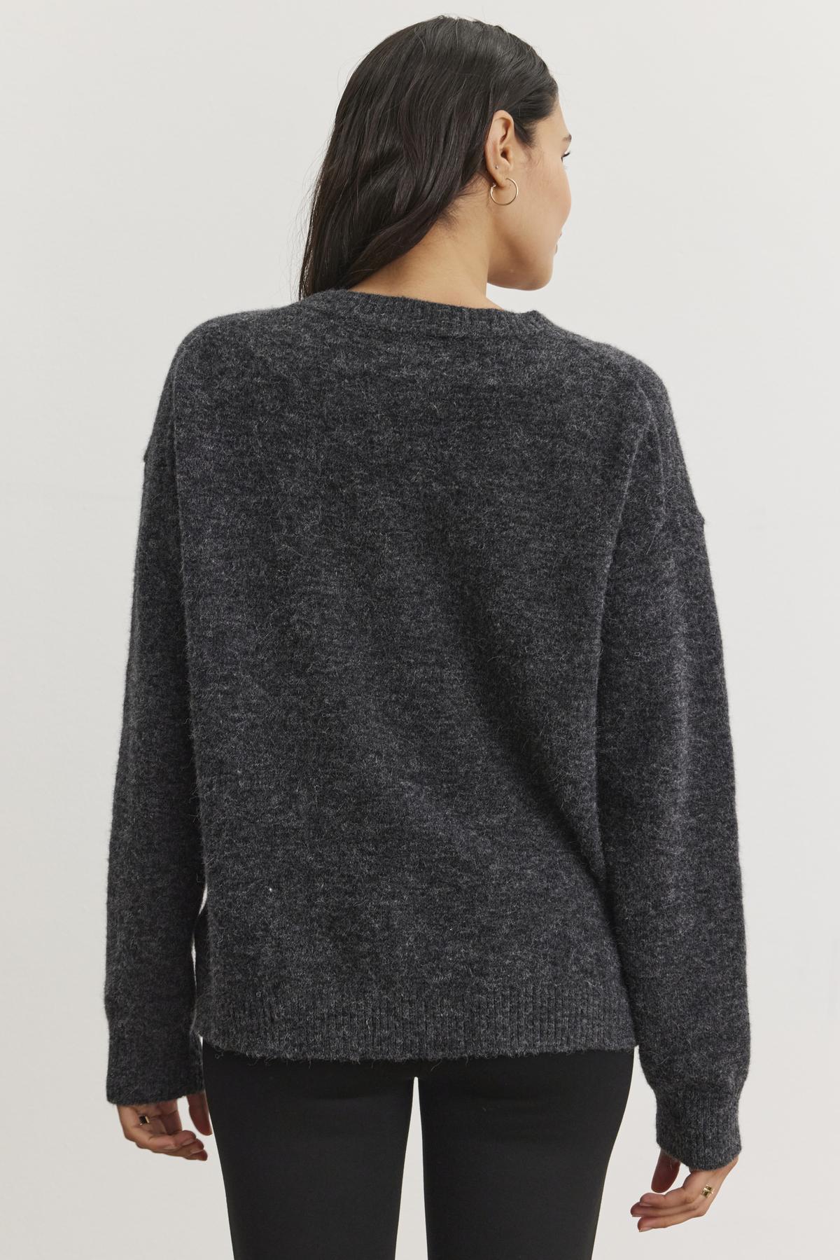   A person facing away, wearing the KELSA ALPACA SWEATER in dark gray from Velvet by Graham & Spencer and black pants, with long dark hair. 