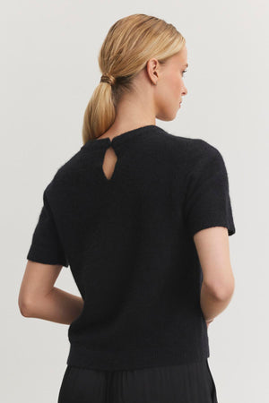 A person with blonde hair in a ponytail is shown from the back wearing the LAYTON ALPACA SWEATER by Velvet by Graham & Spencer, which features short sleeves and a small back keyhole detail.