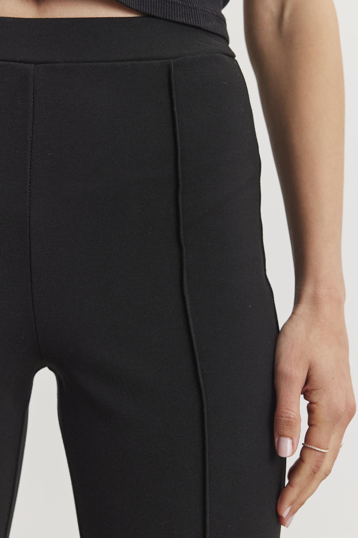   Close-up of a person wearing the ALBEE PONTE PANT by Velvet by Graham & Spencer, featuring visible stitching in stretch ponte fabric, with their right hand resting at their side. 