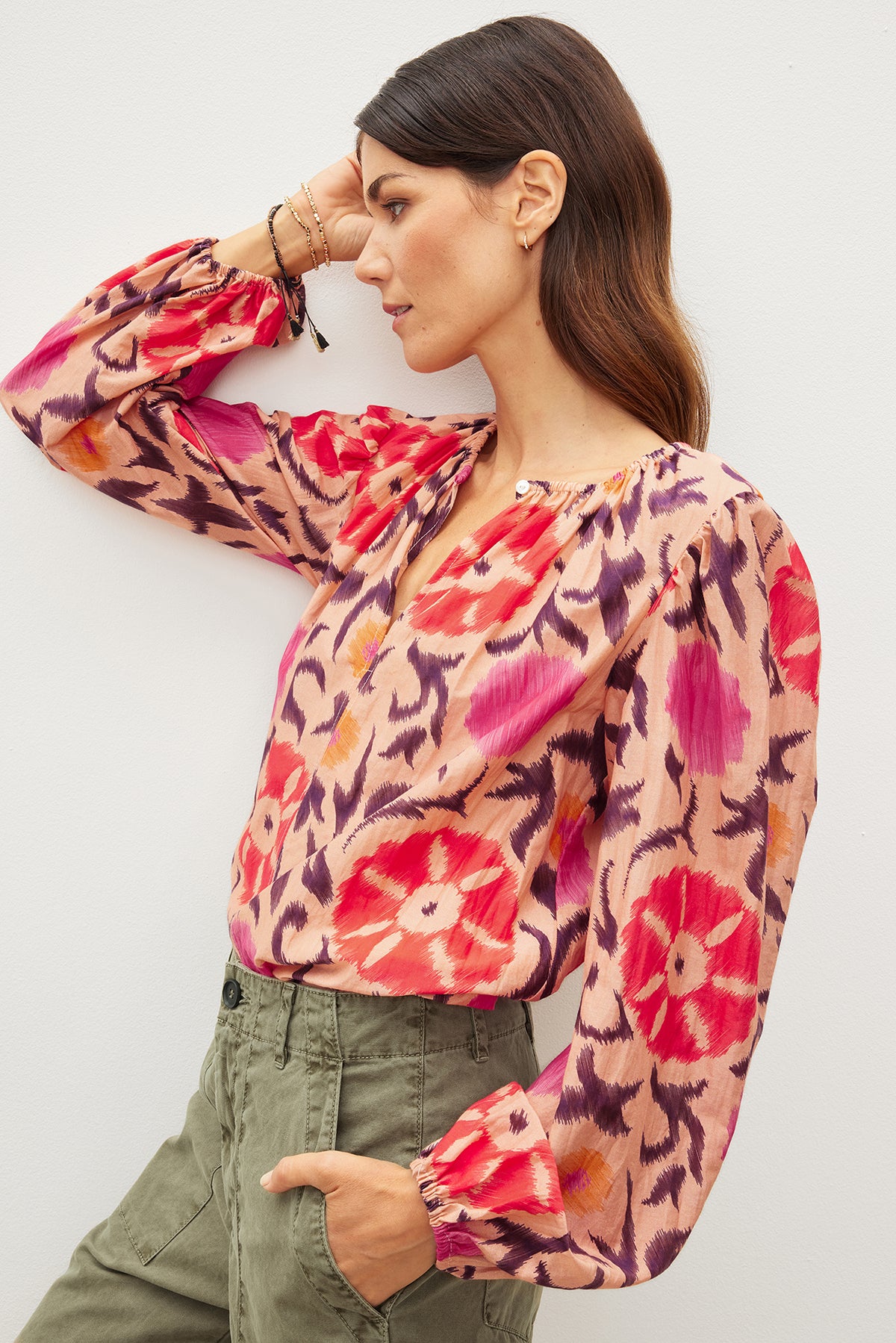   A woman in a FRASER PRINTED SILK COTTON VOILE TOP by Velvet by Graham & Spencer leaning against a wall. 