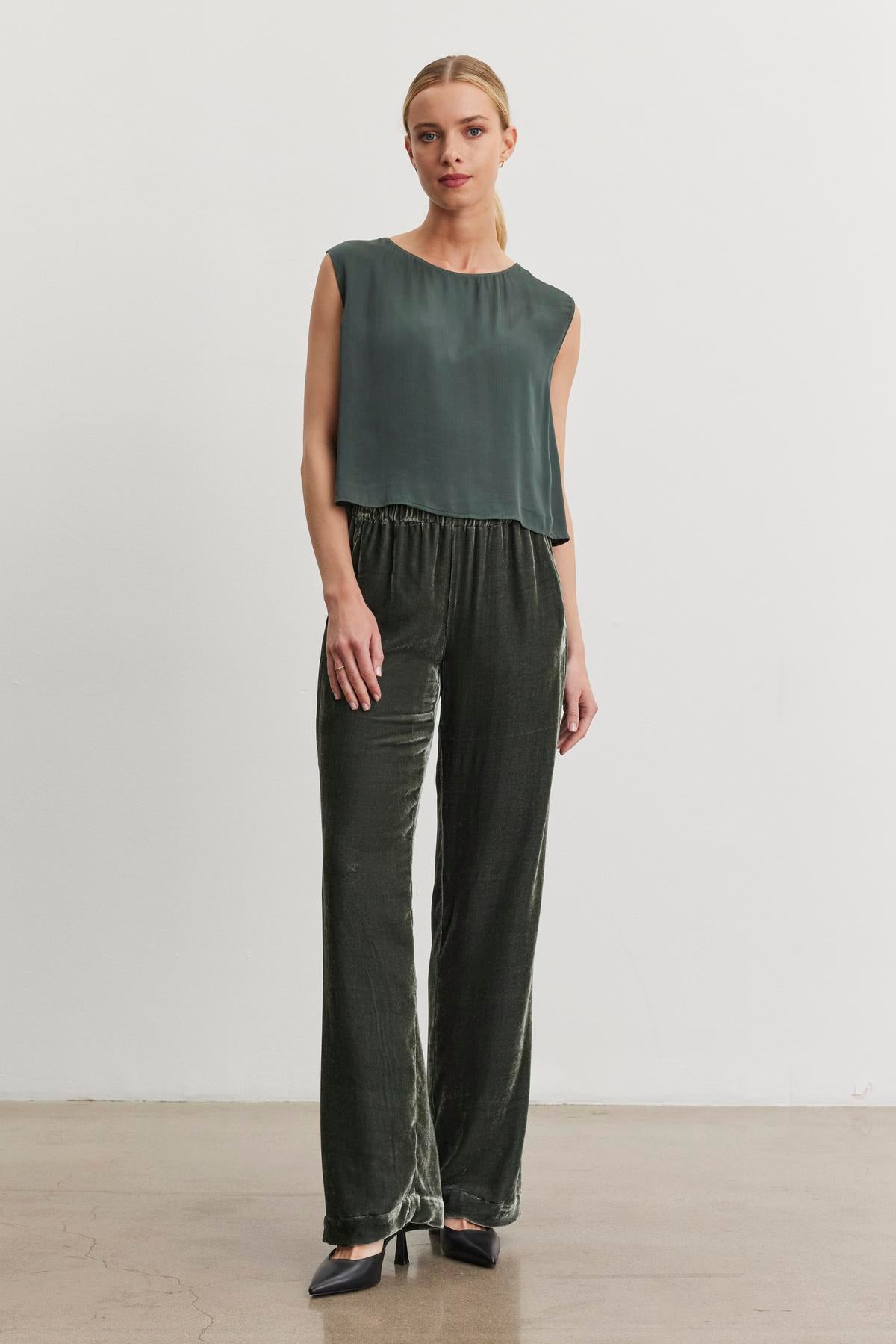   A person wearing a sleeveless dark green top and the Sorine Silk Velvet Pant from Velvet by Graham & Spencer stands against a plain white background. 