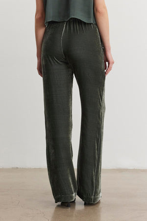 A person wearing the SORINE SILK VELVET PANT by Velvet by Graham & Spencer, along with a matching top, is viewed from the back while standing on a polished floor.