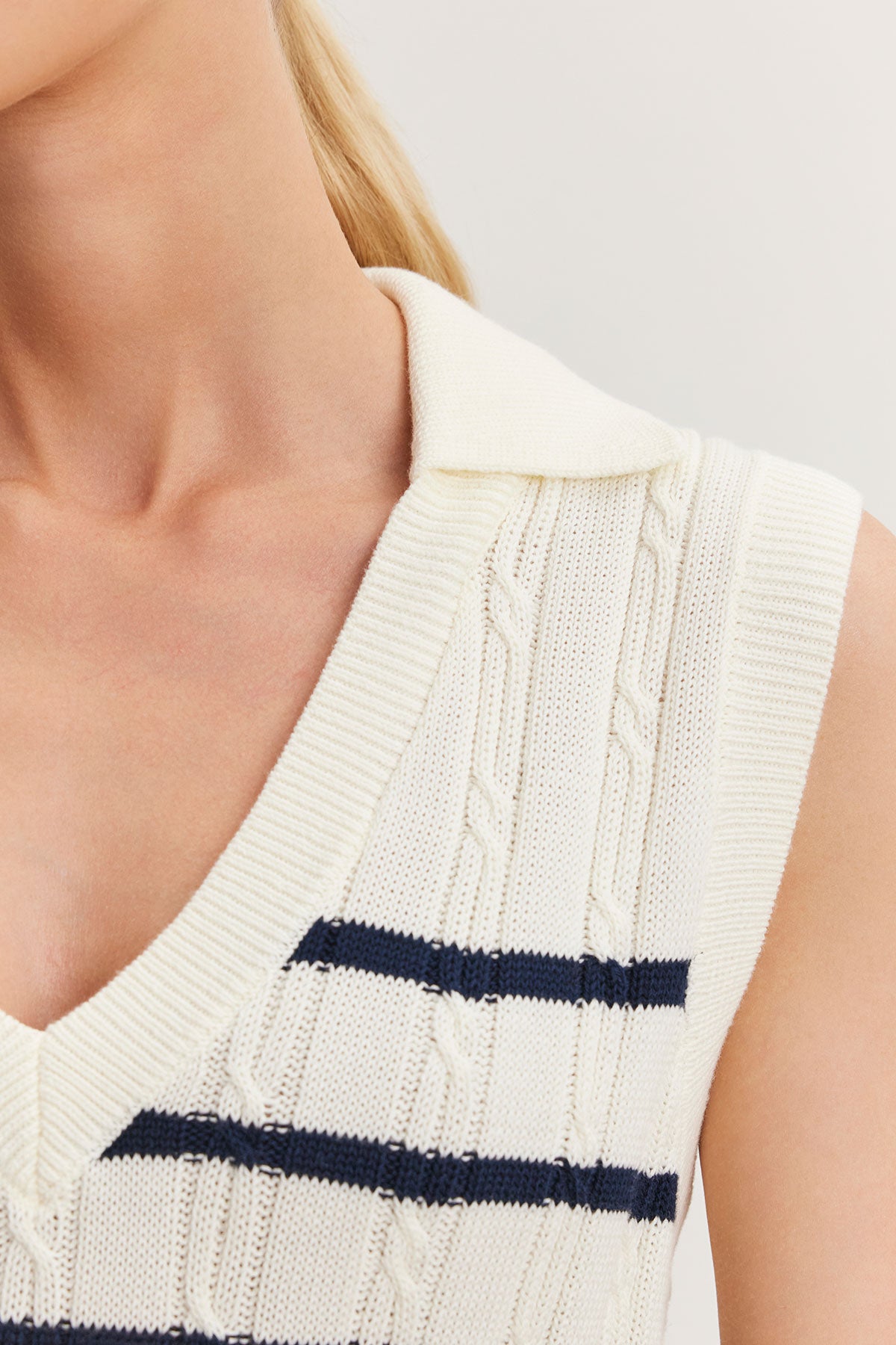 Close-up of a woman wearing a Velvet by Graham & Spencer WENDY SWEATER VEST in cream-colored cable knit with a navy blue stripe detail.-36998738018497