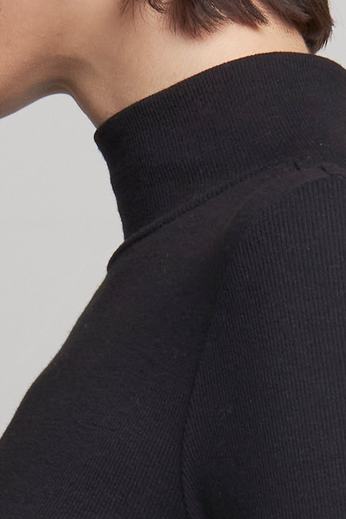   Close-up of a person wearing the HELMS TEE by Velvet by Jenny Graham, featuring a ribbed texture and accentuating the neck and shoulder area. 