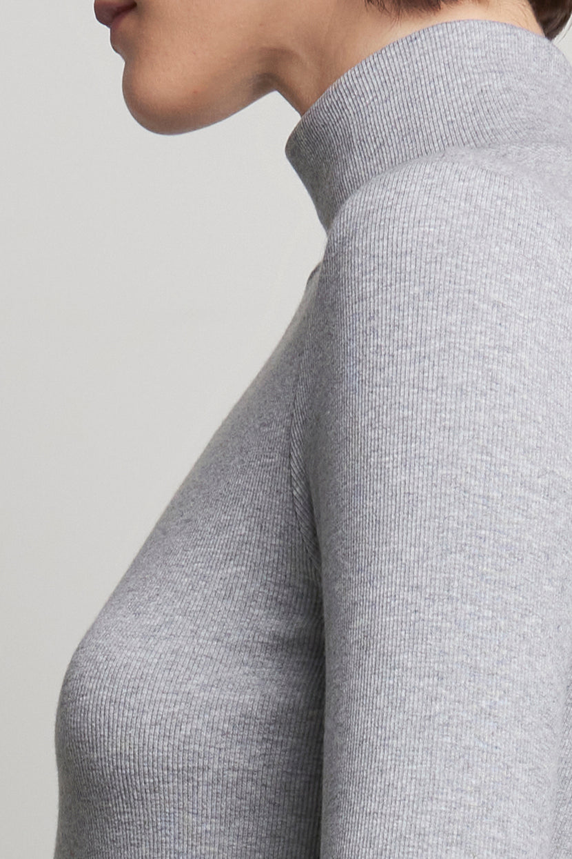 Close-up of a person wearing the HELMS TEE, a gray ribbed turtleneck by Velvet by Jenny Graham, facing left against a plain background.