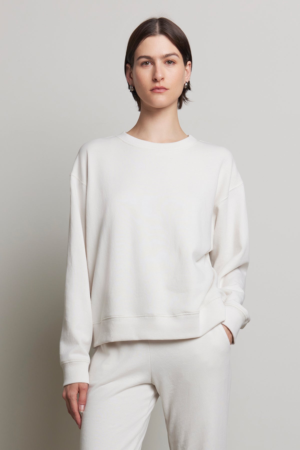   A person wearing the YNEZ SWEATSHIRT and pants from Velvet by Jenny Graham, crafted from organic cotton, stands against a plain background, looking at the camera. 