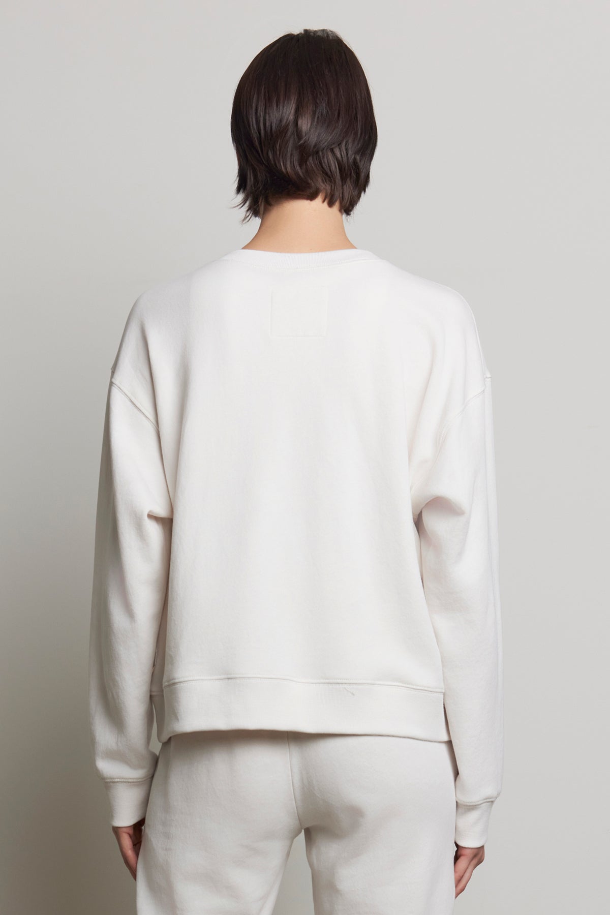   A person is seen from the back against a plain background, wearing the YNEZ SWEATSHIRT by Velvet by Jenny Graham along with matching pants, both made from sustainable fabric. 