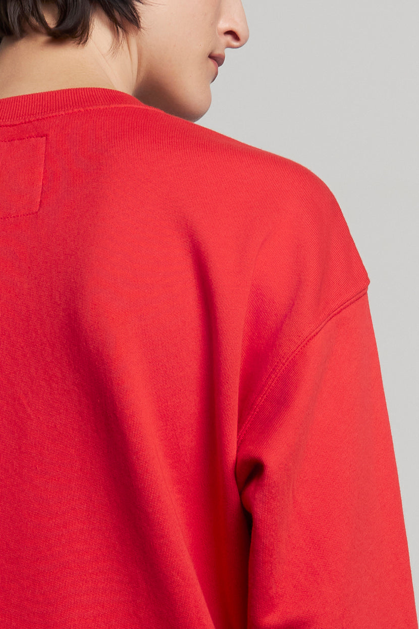 A person wearing the YNEZ SWEATSHIRT from Velvet by Jenny Graham, crafted from organic cotton and in a vibrant red color, is shown from the back with their head turned slightly to the side.