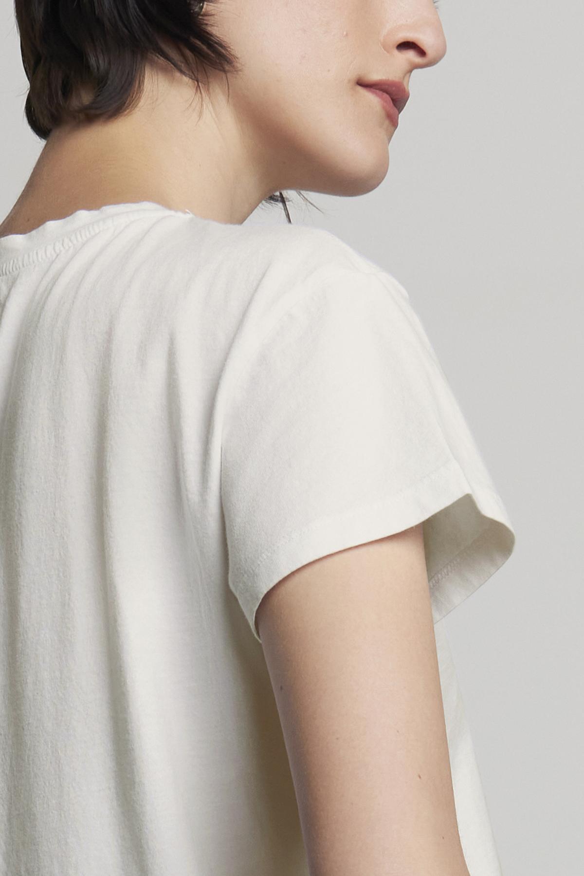   A person with short hair is shown from the side, wearing a relaxed-fit TOPANGA TEE in classic white with short sleeves, made of organic cotton from Velvet by Jenny Graham. 