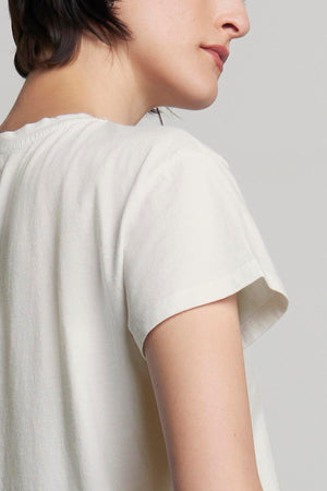 A person with short hair is shown from the side, wearing a relaxed-fit TOPANGA TEE in classic white with short sleeves, made of organic cotton from Velvet by Jenny Graham.