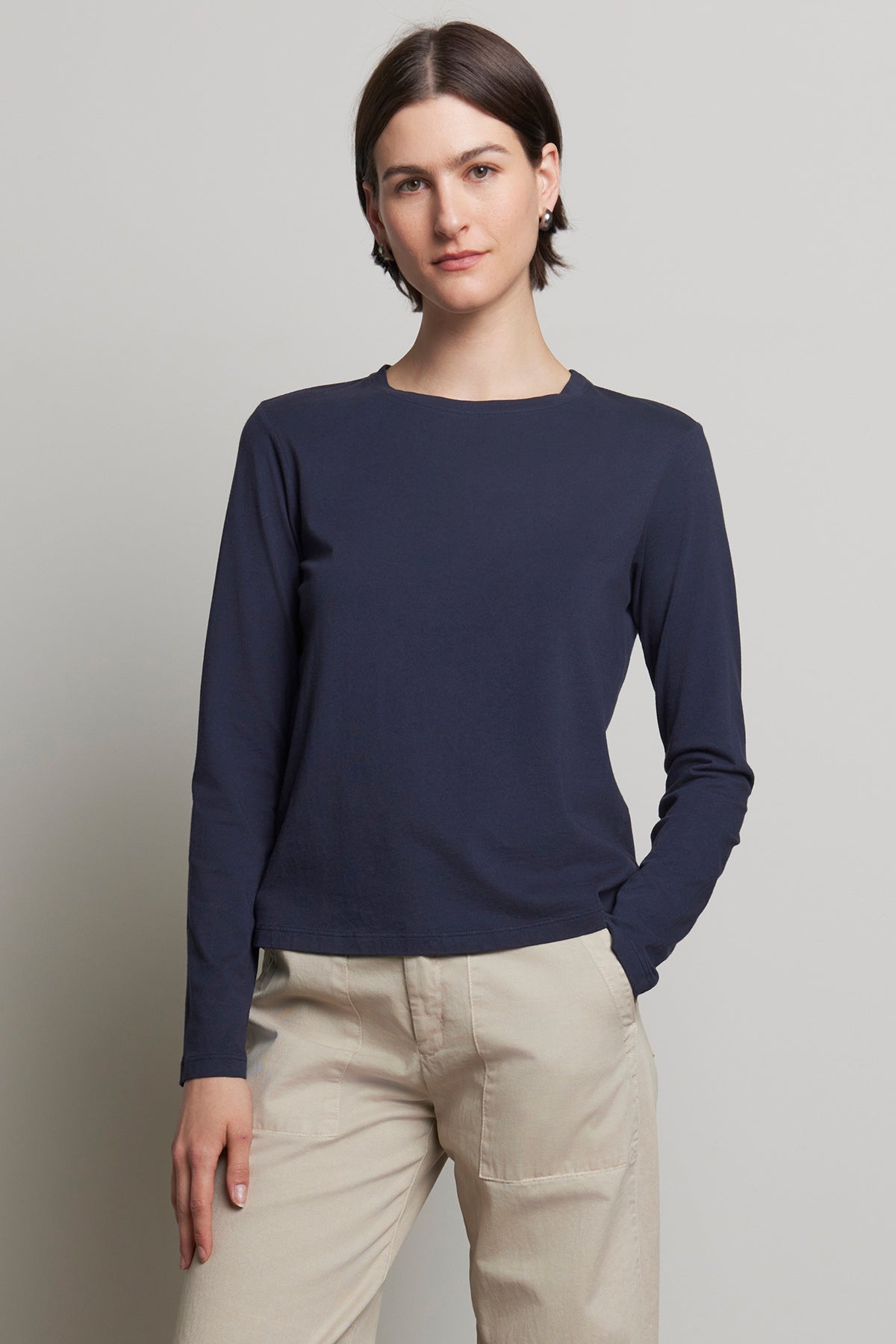   A person clad in the relaxed fit VICENTE TEE by Velvet by Jenny Graham, paired with beige pants, stands against a plain background. 