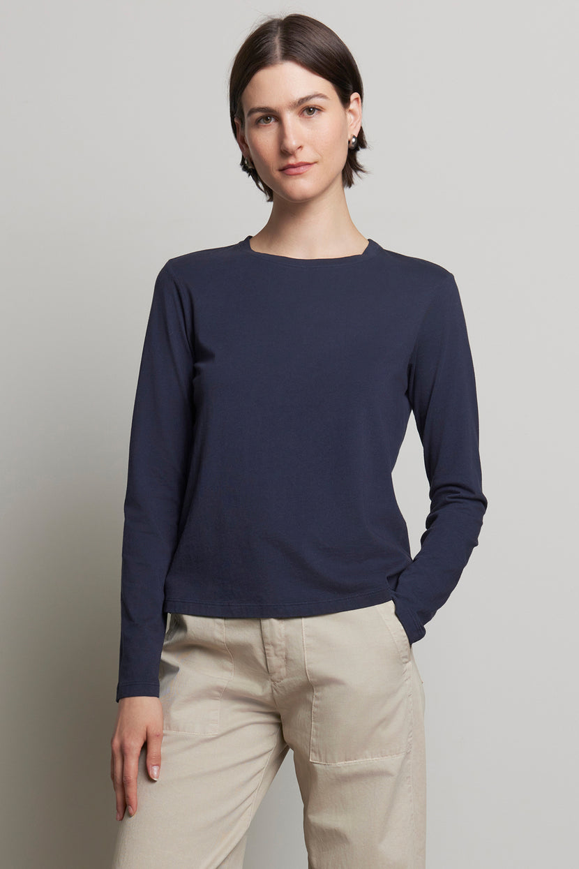 A person clad in the relaxed fit VICENTE TEE by Velvet by Jenny Graham, paired with beige pants, stands against a plain background.