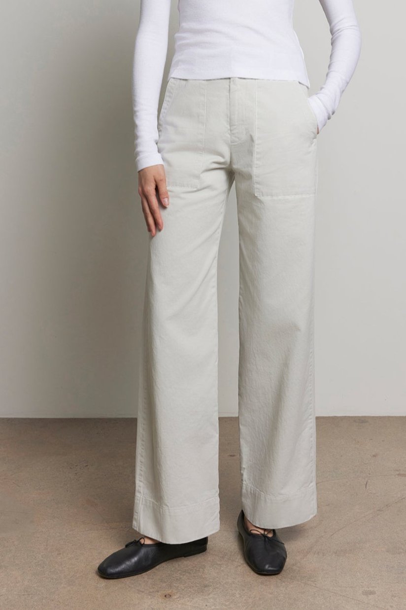 A person standing in a white turtleneck and Velvet by Jenny Graham's VENTURA PANT, which features a utilitarian vibe, with hands in pockets against a neutral background.-38318619132097