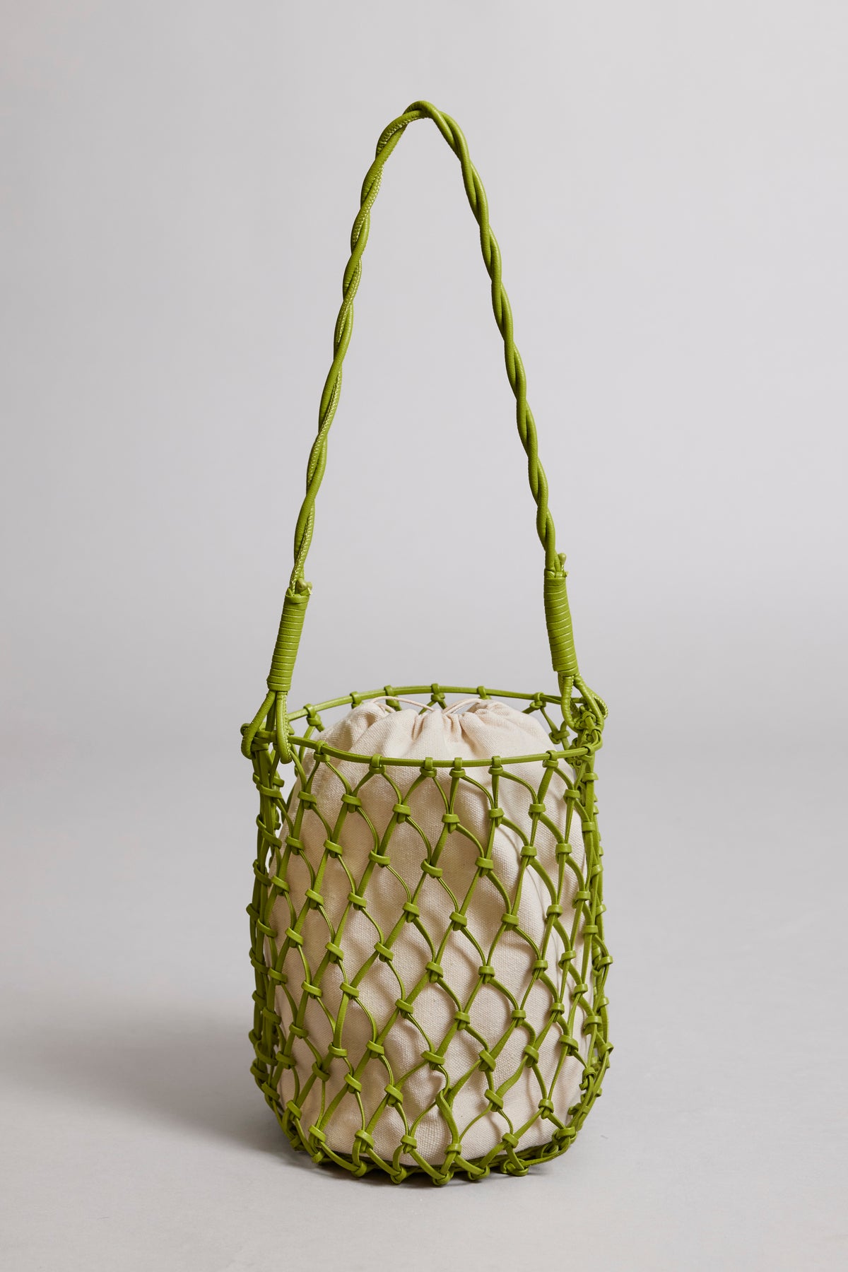   A lime green Velvet by Graham & Spencer mesh-designed tote bag with a braided strap and a light beige drawstring pouch inside, set against a neutral background. 