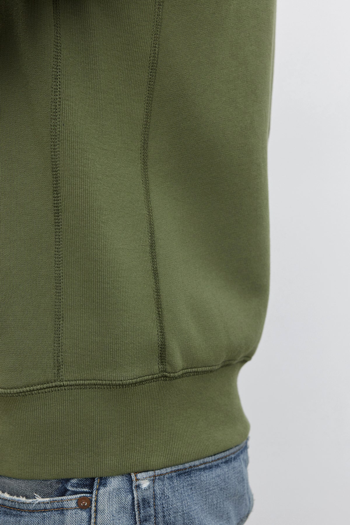 Close-up of a person wearing the REN HOODIE by Velvet by Graham & Spencer and faded blue jeans. The cotton fleece sweatshirt covers most of the person's torso, giving off a vintage look.-37893745836225