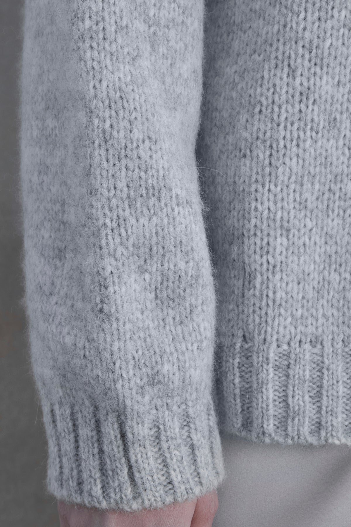   Close-up of the sleeve and ribbed cuff of a light gray CAMBRIA ALPACA SWEATER by Velvet by Jenny Graham, worn by a person. The background is a neutral color. 