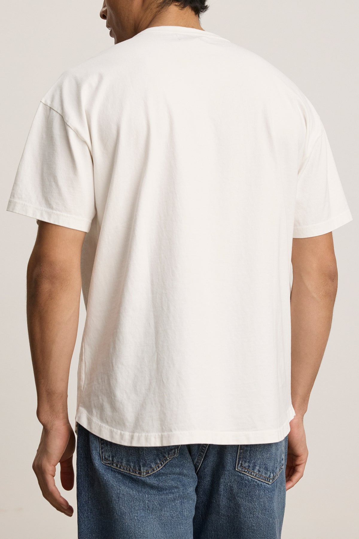 A person in a relaxed fit BRYAN TEE from Velvet by Graham & Spencer, made of structured pima cotton and paired with blue jeans, faces away from the camera, showcasing everyday versatility.-38500197433537