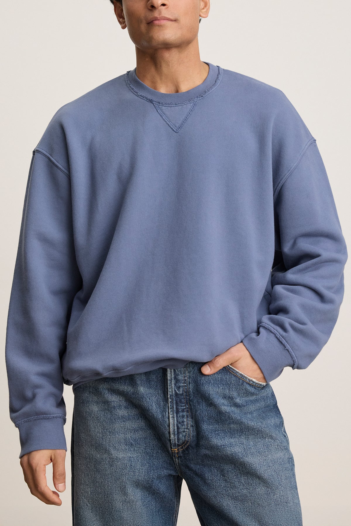   Wearing the FORREST SWEATSHIRT from Velvet by Graham & Spencer in blue cotton fleece with jeans, one hand casually tucked in a pocket, exudes a relaxed fit. 