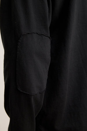 Close-up of a black sleeve from the SLATER TEE by Velvet by Graham & Spencer, crafted from pima cotton jersey with a rectangular elbow patch. This relaxed-fit piece is versatile for any wardrobe.