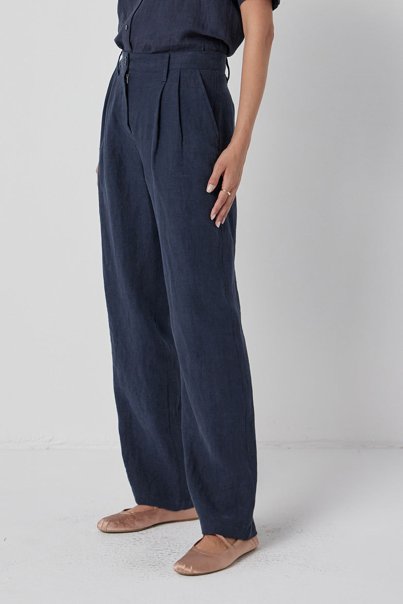 Woman in Velvet by Jenny Graham's POMONA PANT, dark, heavy-weight linen straight-leg pants and tan flats standing against a white background.