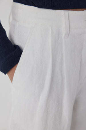 A person wearing white Velvet by Jenny Graham POMONA pants with a hand in the pocket.