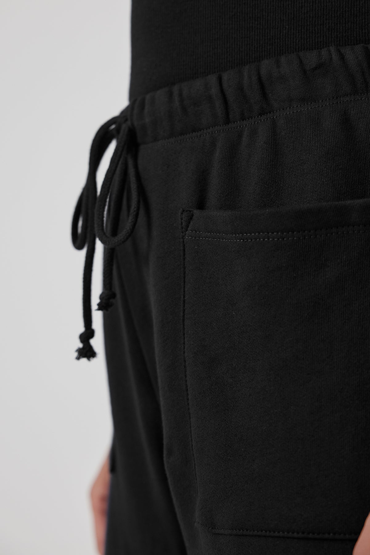 Close-up of the WESTLAKE SWEATPANT by Velvet by Jenny Graham, made from black organic cotton fleece, featuring an elastic drawstring waist and a convenient side pocket.-38208768868545