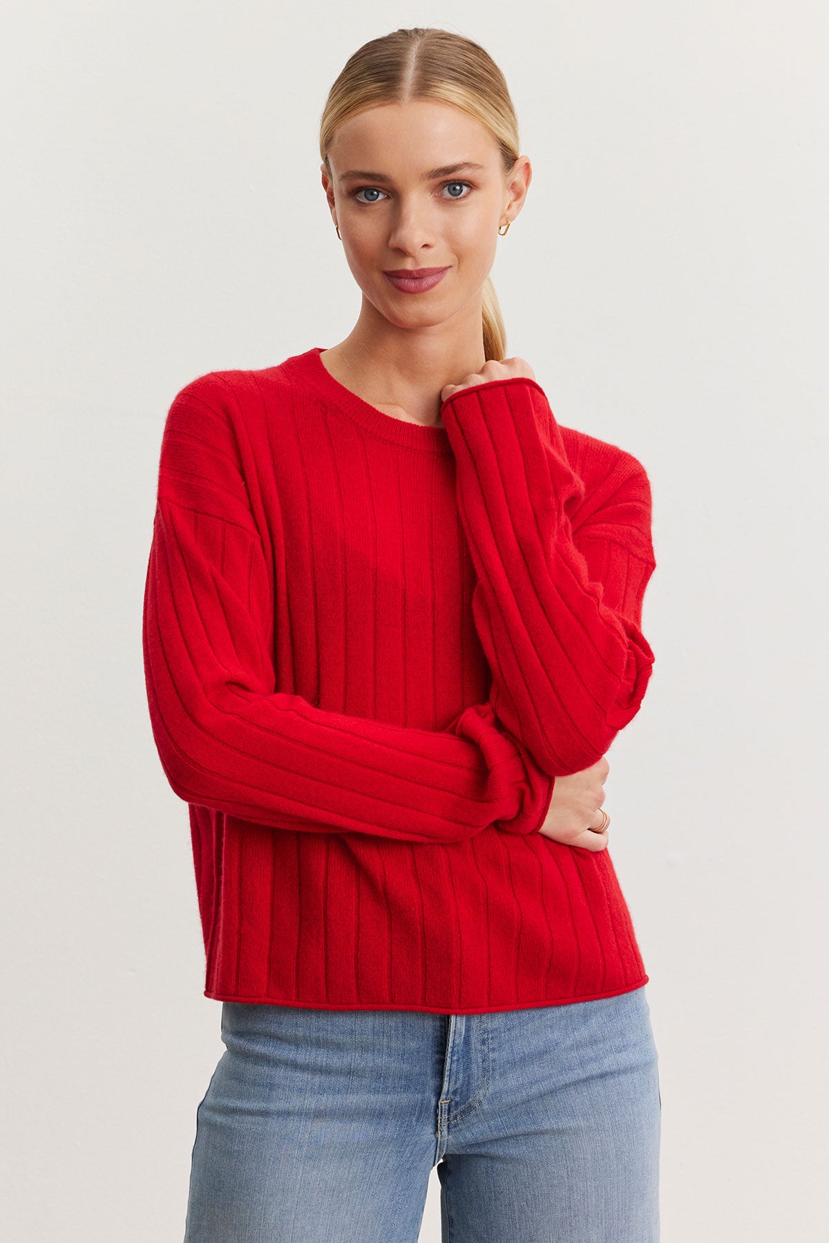   A person wearing the MONICA CASHMERE SWEATER by Velvet by Graham & Spencer, a true wardrobe essential, and blue jeans stands against a plain background. 