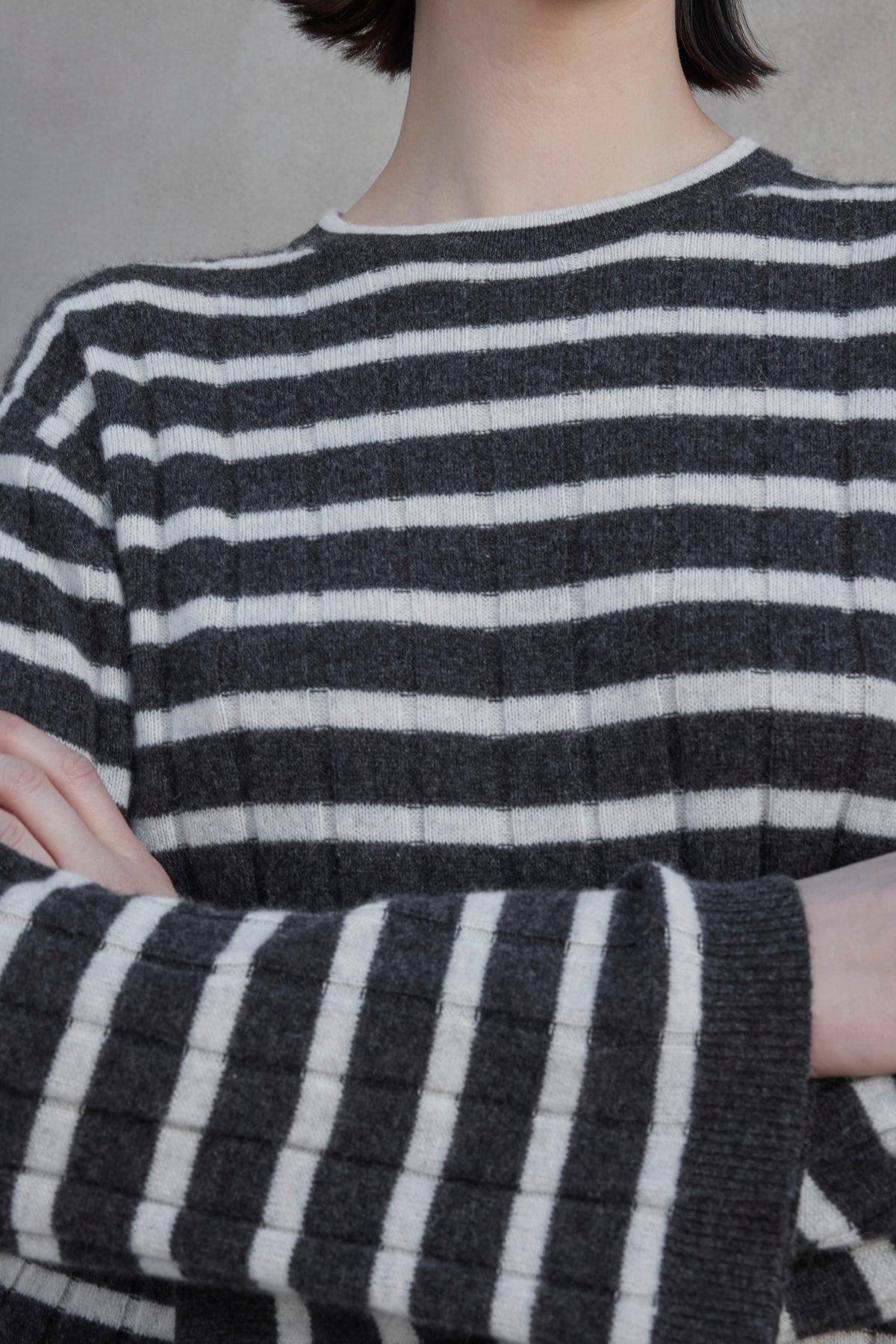 Close-up of a person in the NAPA CASHMERE SWEATER by Velvet by Jenny Graham, featuring a black and white striped pattern, with their arms crossed. Their face is not visible.-37659917287617