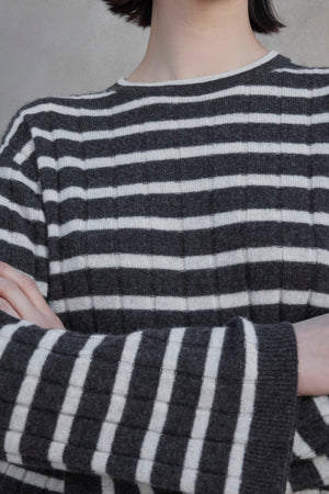 Close-up of a person in the NAPA CASHMERE SWEATER by Velvet by Jenny Graham, featuring a black and white striped pattern, with their arms crossed. Their face is not visible.