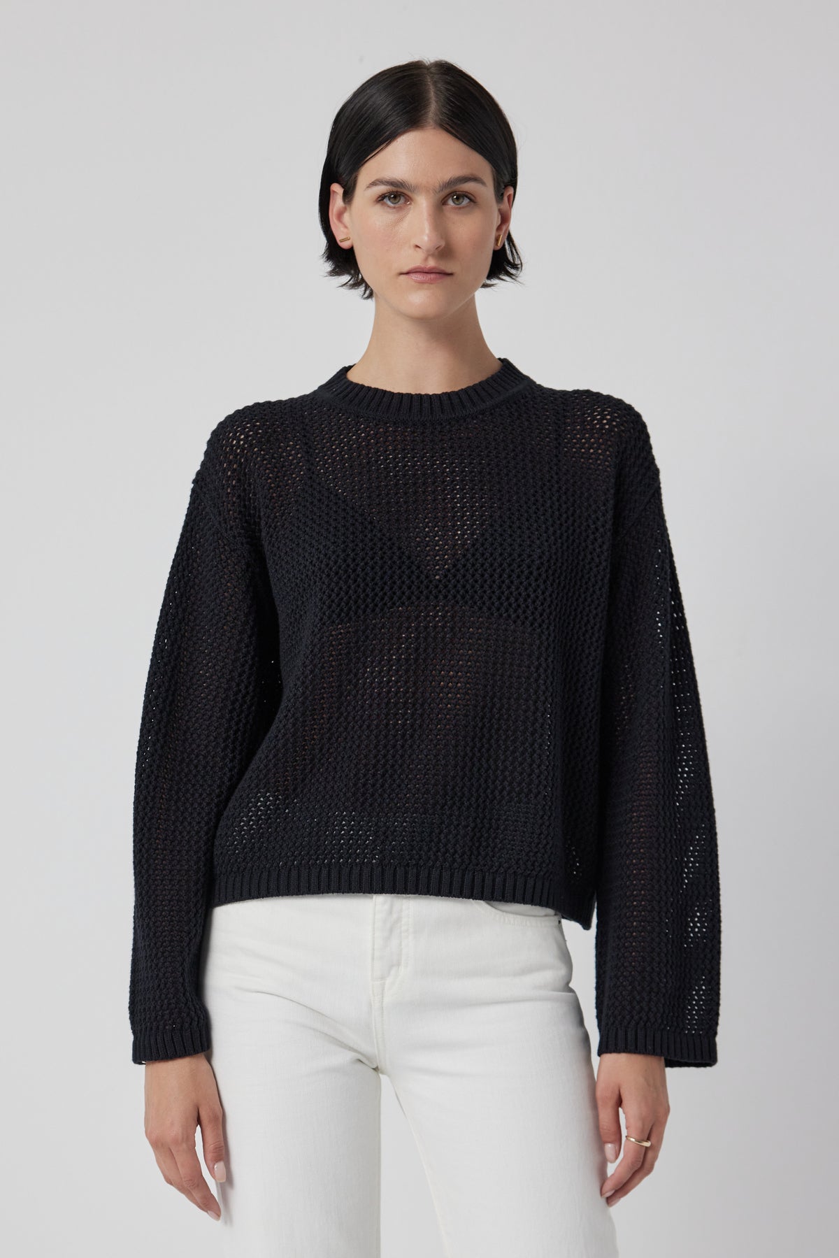   A model wearing a lightweight black KANAN SWEATER by Velvet by Jenny Graham and white jeans. 