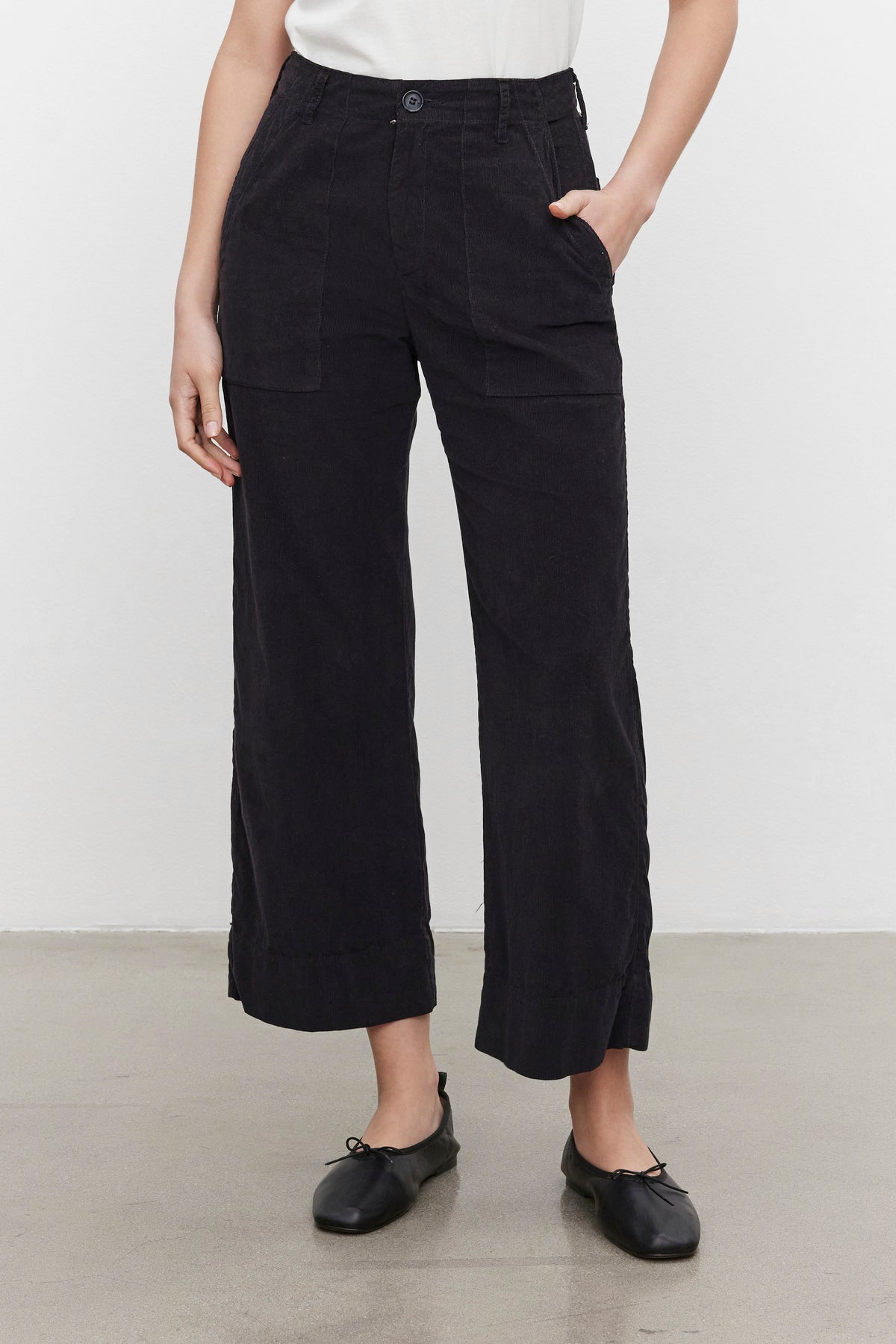   Person wearing VERA CORDUROY PANT by Velvet by Graham & Spencer with black ballet flats, standing against a plain white background. 