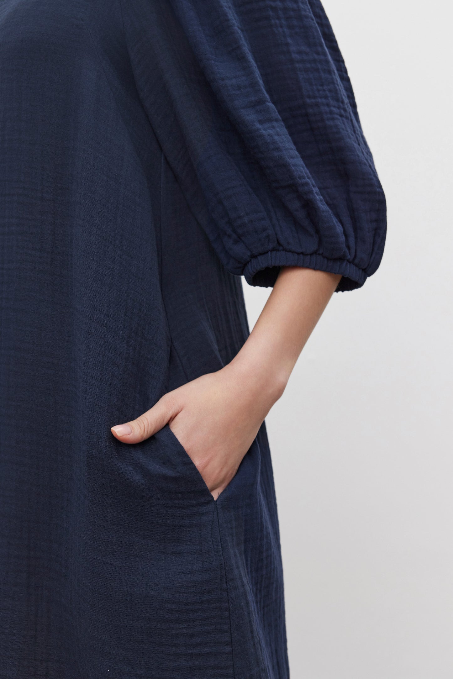 A person donning the KARINA COTTON GAUZE DRESS by Velvet by Graham & Spencer in dark blue, complete with puff sleeves and a convenient pocket, perfect for casual outings.-37629603152065