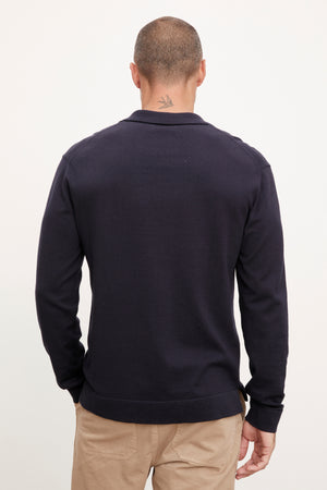 The back view of a man wearing a Velvet by Graham & Spencer navy sweater and khaki pants.