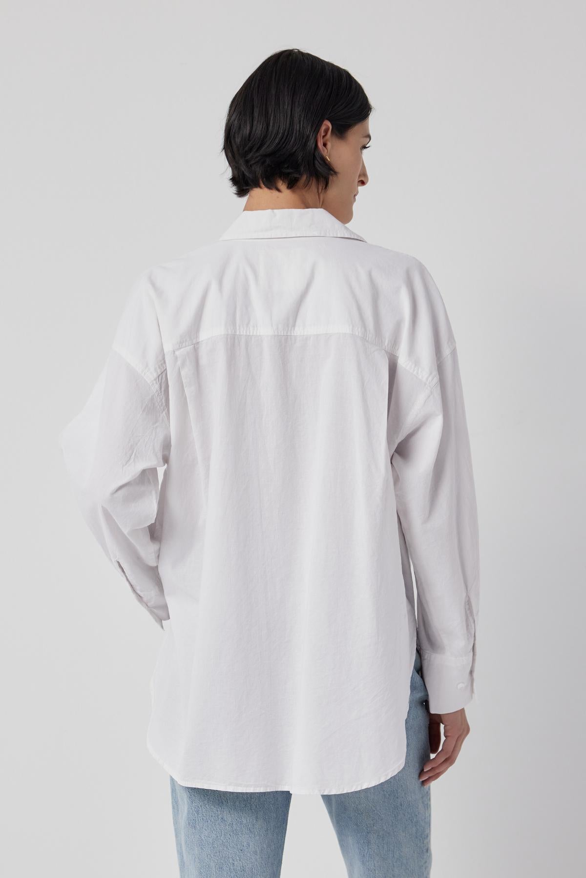   The back view of a woman wearing an oversized Velvet by Jenny Graham Redondo Button-Up Shirt, embracing the borrowed-from-the-boys silhouette fashion trend. 