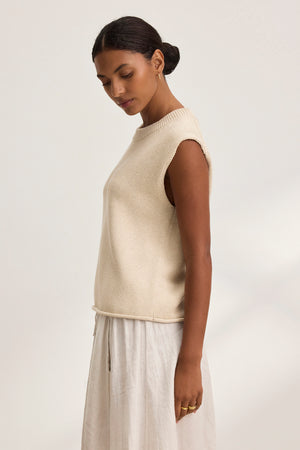 A woman in a PAOLA COTTON CASHMERE SWEATER VEST by Velvet by Graham & Spencer and a white skirt stands sideways against a plain background.