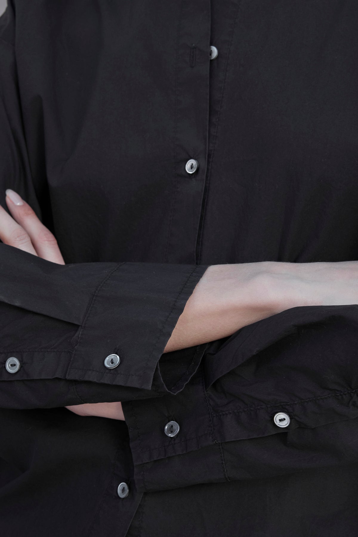   Person wearing a black DAKOTA SHIRT by Velvet by Jenny Graham is crossing their arms, with a partial view showing from shoulders to waist. 