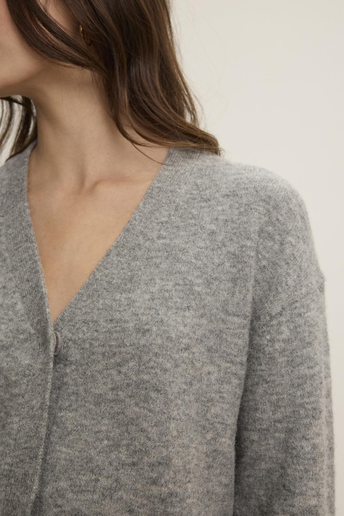   A person wearing the MARTI ALPACA CARDIGAN by Velvet by Graham & Spencer, featuring ribbed trims in a soft gray alpaca blend, partially visible from shoulders to mid-chest against a plain background. 