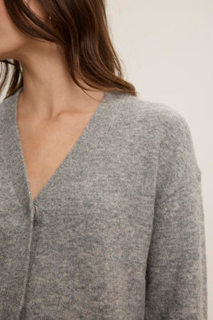 A person wearing the MARTI ALPACA CARDIGAN by Velvet by Graham & Spencer, featuring ribbed trims in a soft gray alpaca blend, partially visible from shoulders to mid-chest against a plain background.