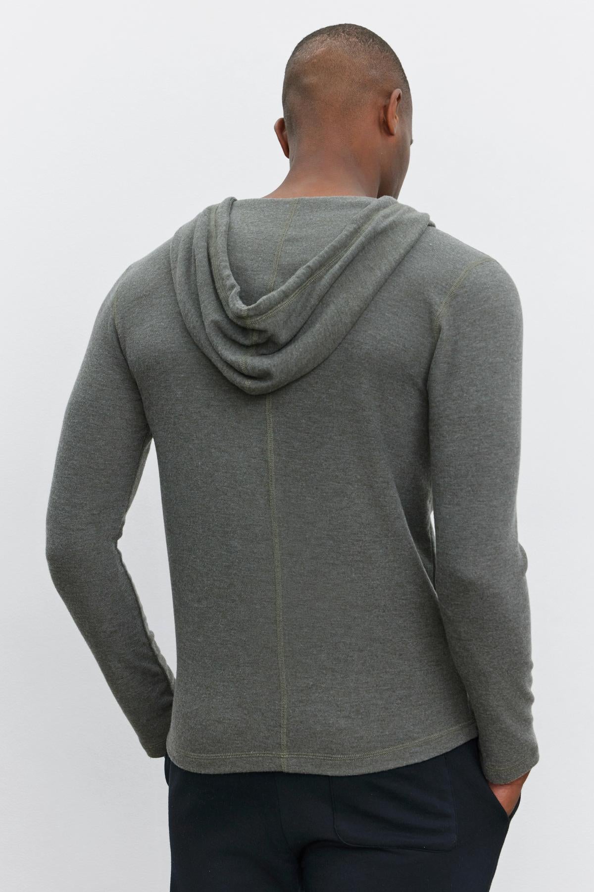   A person shown from the back, wearing the cozy LOUDON HOODIE in gray by Velvet by Graham & Spencer and dark pants, standing against a plain background. 