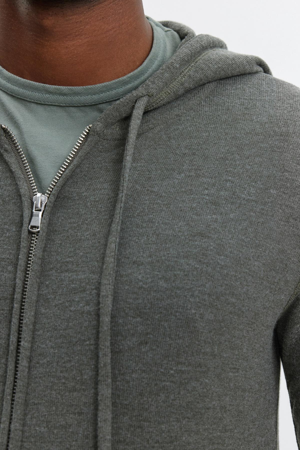   Close-up of a person wearing a light green LOUDON HOODIE by Velvet by Graham & Spencer over a matching green shirt. Only the lower part of the face, neck, and upper torso are visible. 