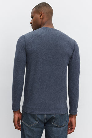 A person with short hair wearing a long-sleeved, dark gray RYLAND HENLEY from Velvet by Graham & Spencer and jeans stands with their back to the camera.