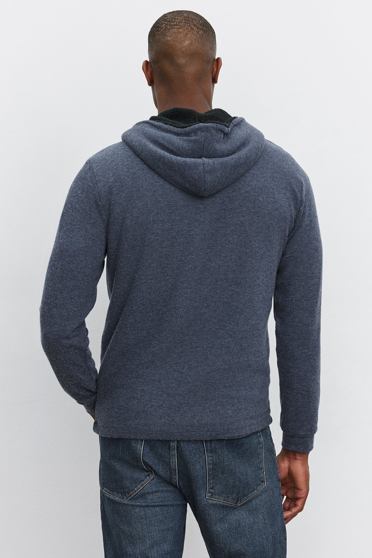   A man wearing a Velvet by Graham & Spencer SALVADORE HOODIE and blue jeans is shown from the back, standing against a plain white background. 