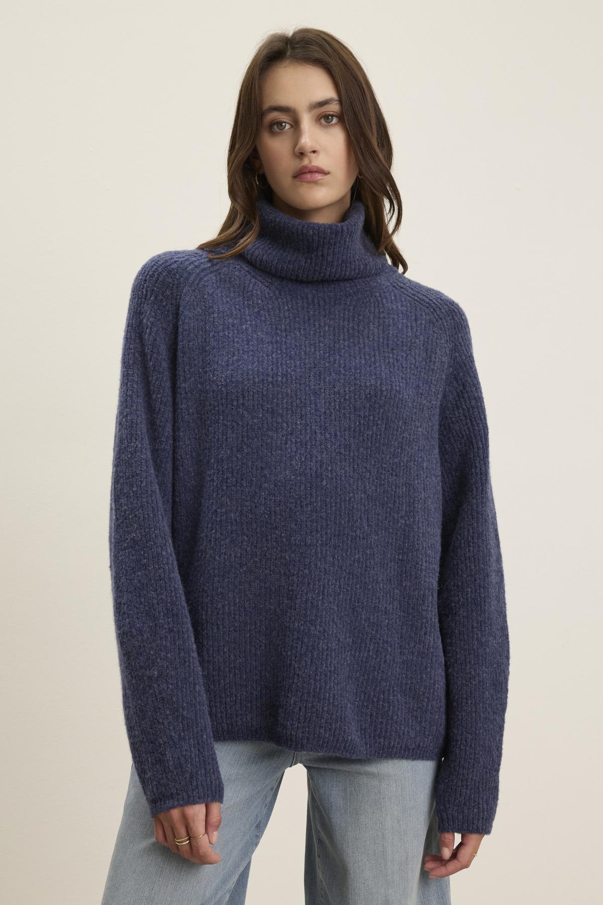 A person is wearing the JUDITH TURTLENECK SWEATER from Velvet by Graham & Spencer, styled with light blue jeans, standing against a plain background.-38303601098945