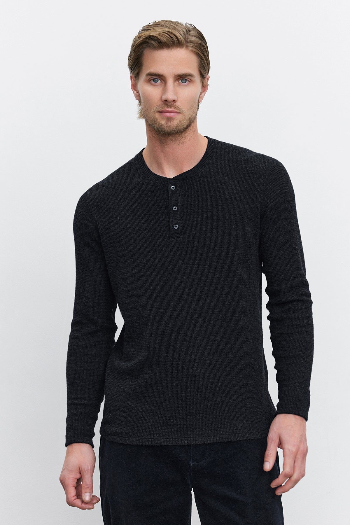   A man with short hair stands against a plain white background, wearing the AMBROSE HENLEY from Velvet by Graham & Spencer. This triblend cozy thermal fabric henley features a three-button placket. 