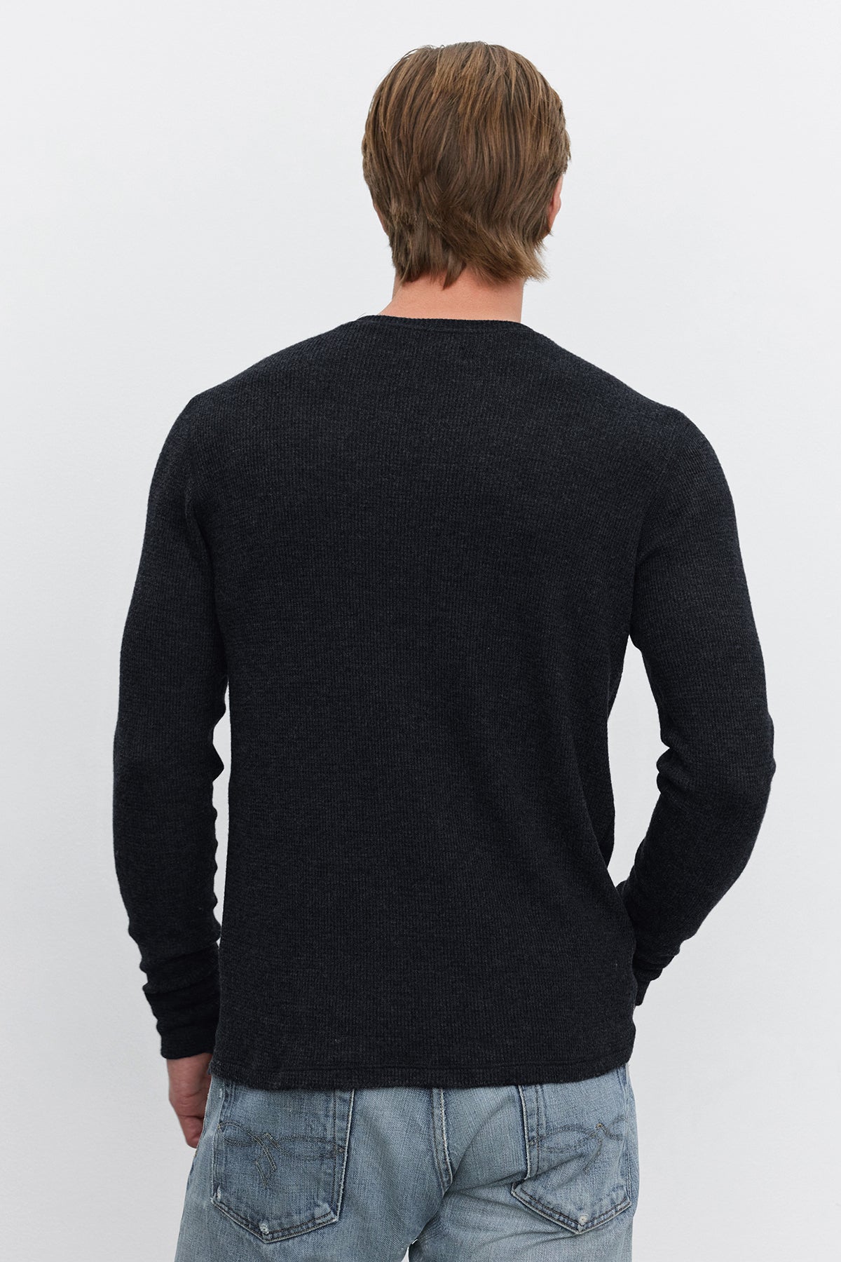   A person with short, light brown hair, wearing the TOBIAS CREW black long-sleeve thermal shirt by Velvet by Graham & Spencer and blue jeans, is shown from the back against a plain white background. 