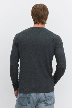 A person with short brown hair is shown from the back, wearing a long-sleeved TOBIAS CREW in dark grey textured fabric made of triblend cozy thermal material by Velvet by Graham & Spencer, paired with light blue jeans.