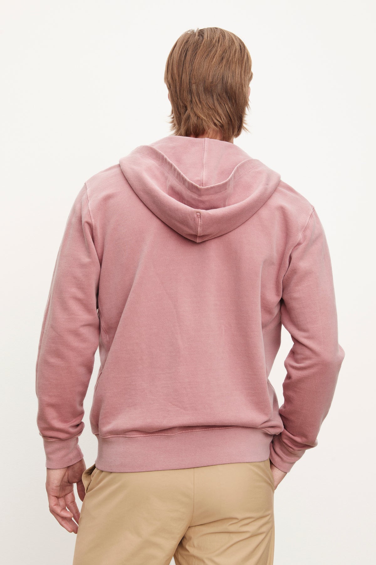   Man standing with his back to the camera, wearing a Velvet by Graham & Spencer VINCENT HOODIE and beige pants against a white background. 