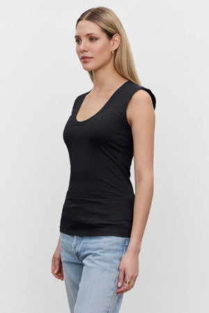 A person wearing a laid-back tank and light blue jeans stands against a plain white background, exuding effortless style with their Velvet by Graham & Spencer ESTINA TANK TOP.
