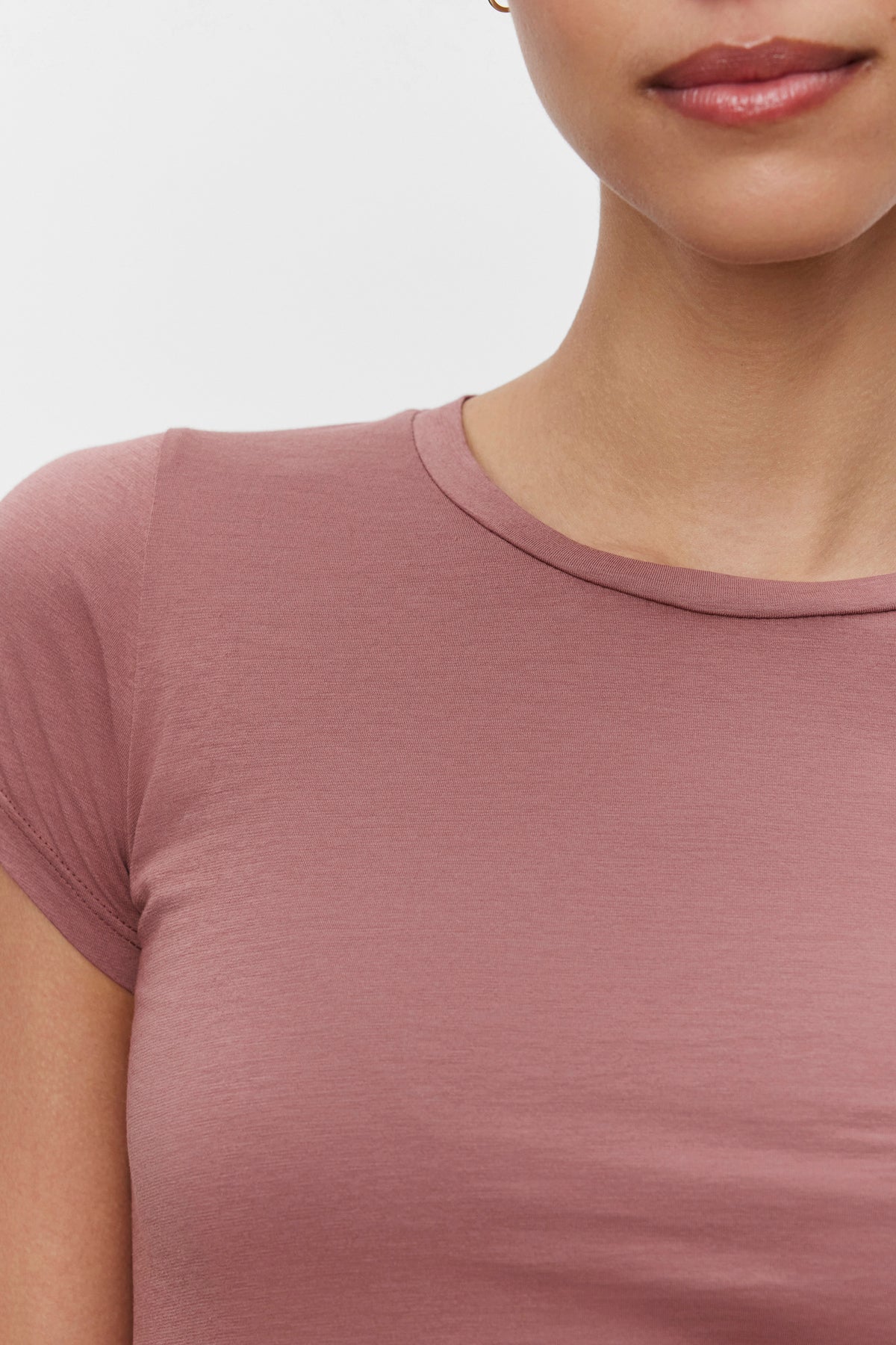 Close-up image of a person wearing an ultra-soft gauzy whisper mauve Velvet by Graham & Spencer JEMMA TEE, focusing on the upper torso and part of the face with minimal details visible.-37386168795329